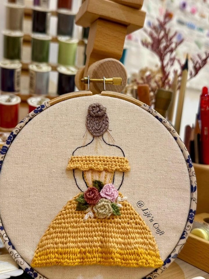Life'n Craft 学员的刺绣作品 —— 绷架上的黄裙少女，背景是工作室的线轴与工具